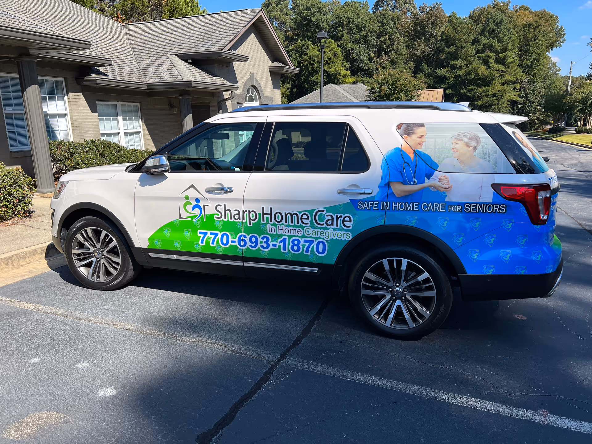 White Sharp Home Care van with blue-green graphics parked in a lot beside a building.