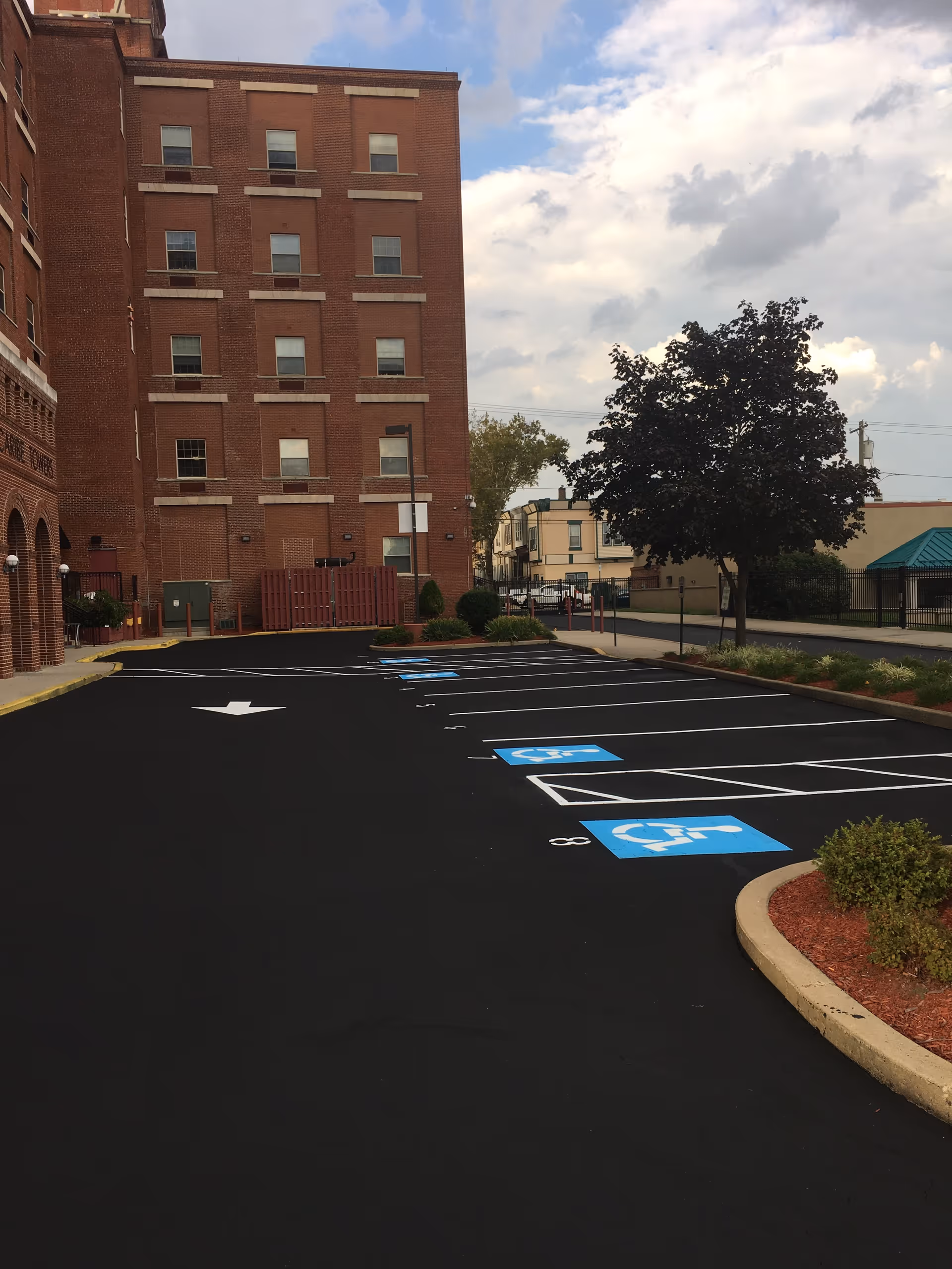 Exterior view of a brick senior living facility with a paved accessible parking lot.