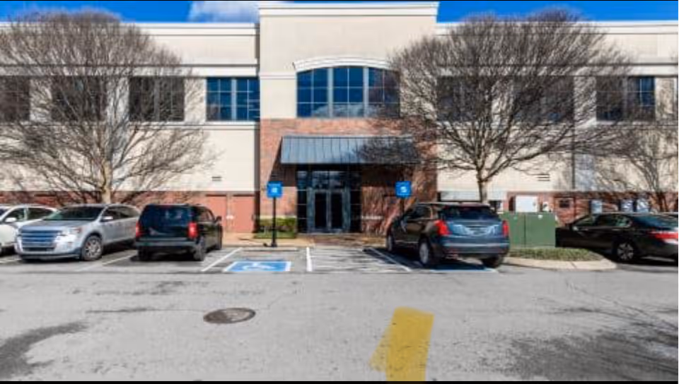 Front exterior of a two-story senior care facility with parked cars in front.