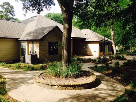 Curved walkway leads to brick Sunrise Senior Care Home entrance with surrounding trees and landscaping.