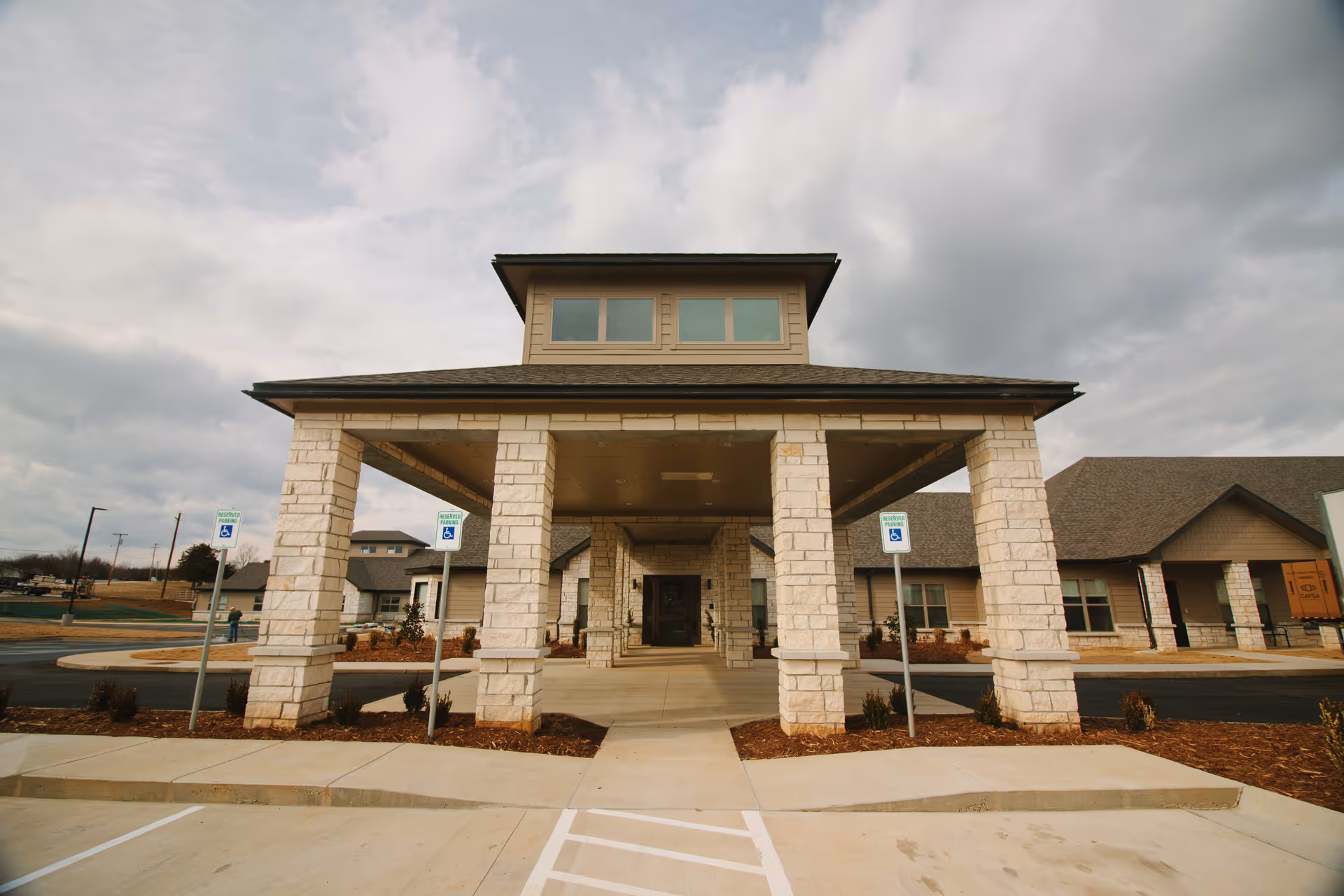 Stone-clad entrance with tall columns and a covered drop-off at a senior living facility.