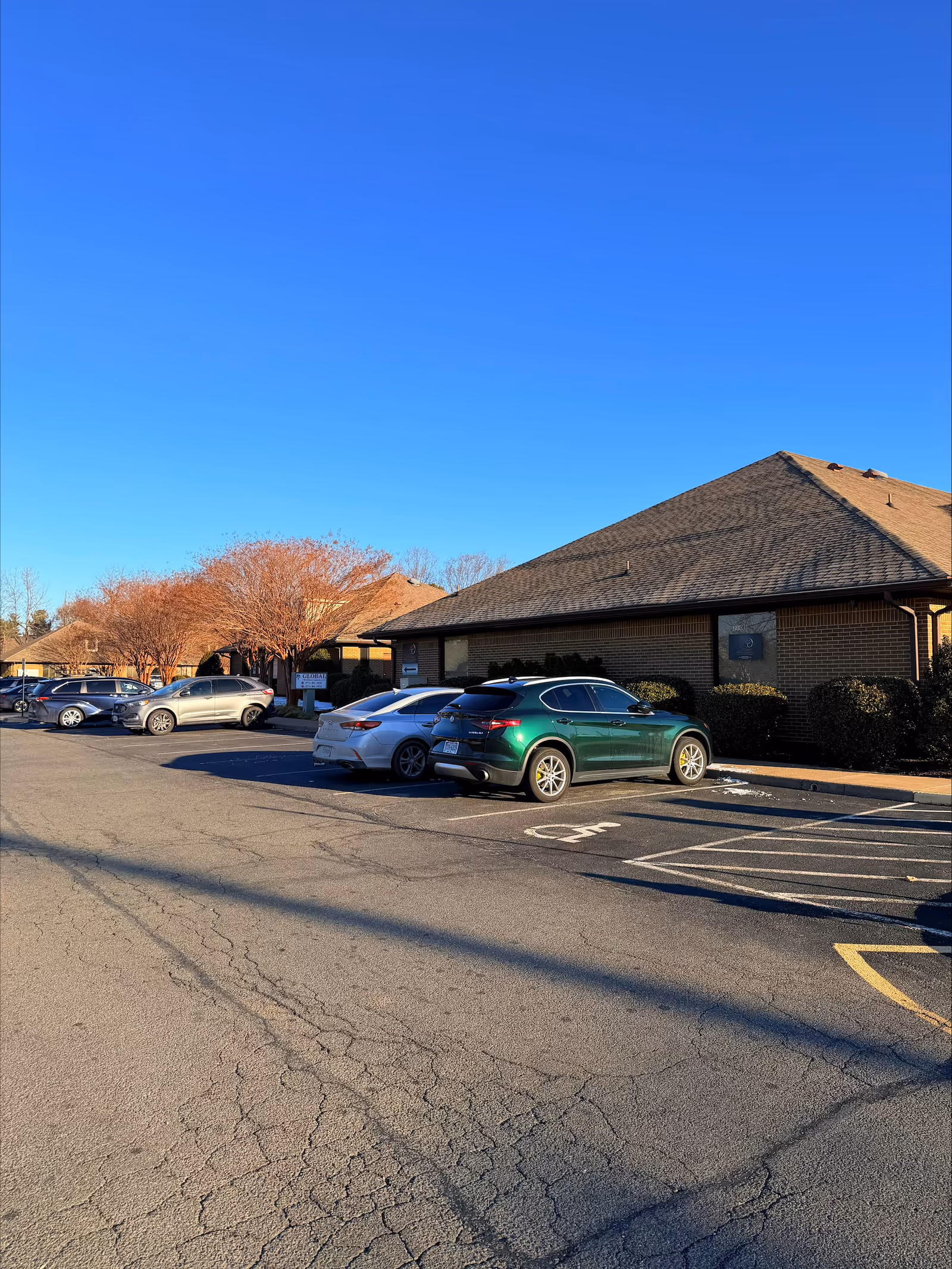 Parking lot in front of a brick senior living facility under a clear blue sky