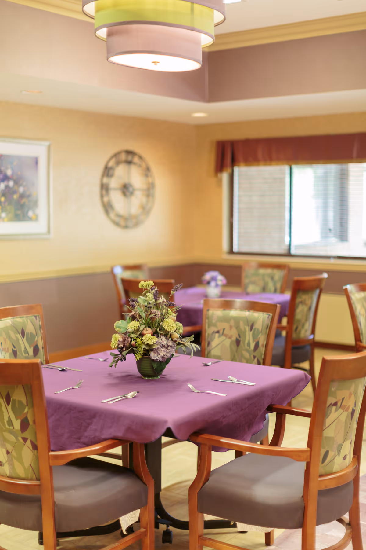 Softly lit dining room with purple tablecloths and floral centerpieces.