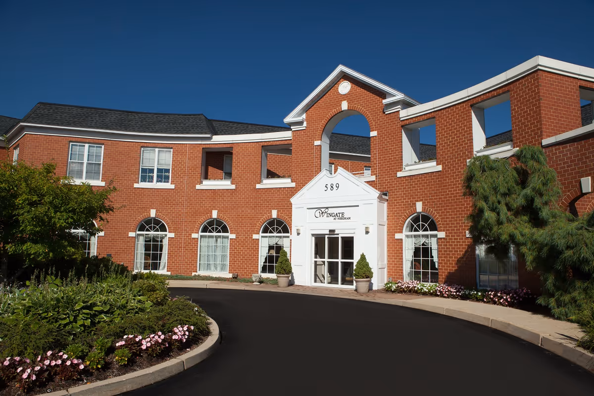 Brick Wingate at Needham building with arched windows and a curved driveway.