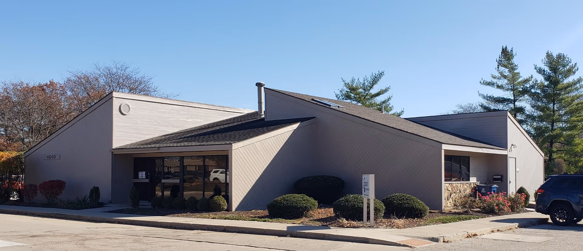 Front exterior of a modern senior care facility with landscaped entry and shrubs.