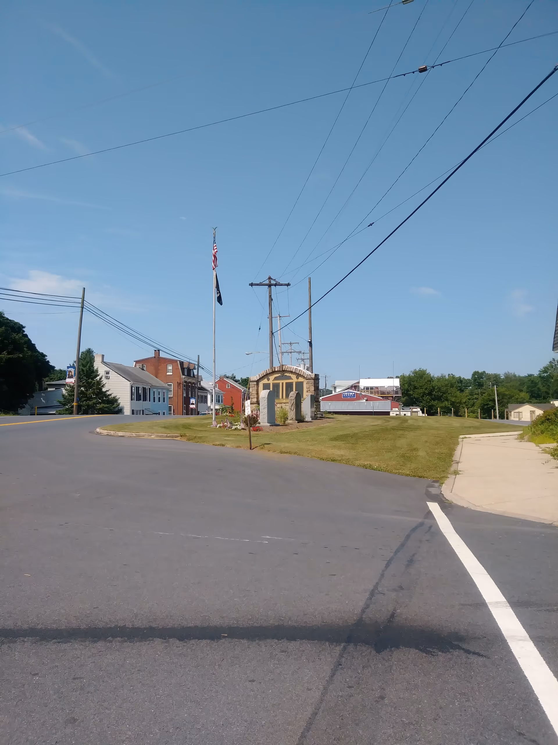 Wide street view of a small town with a flagpole and utility poles under clear sky