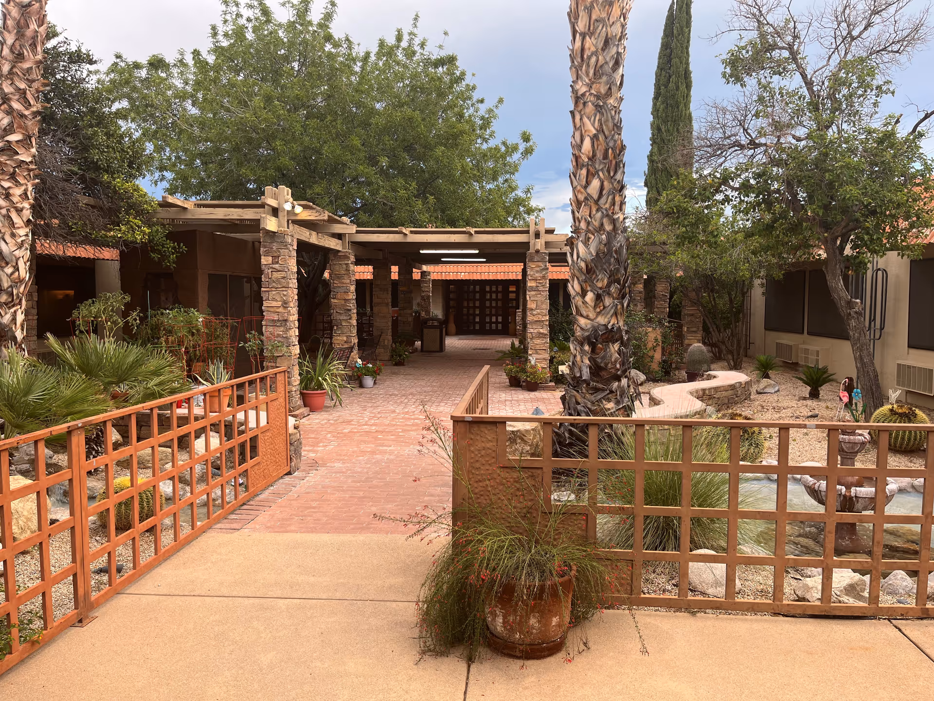 Outdoor courtyard of Santa Rita Nursing and Rehabilitation Center with brick path and palm trees.