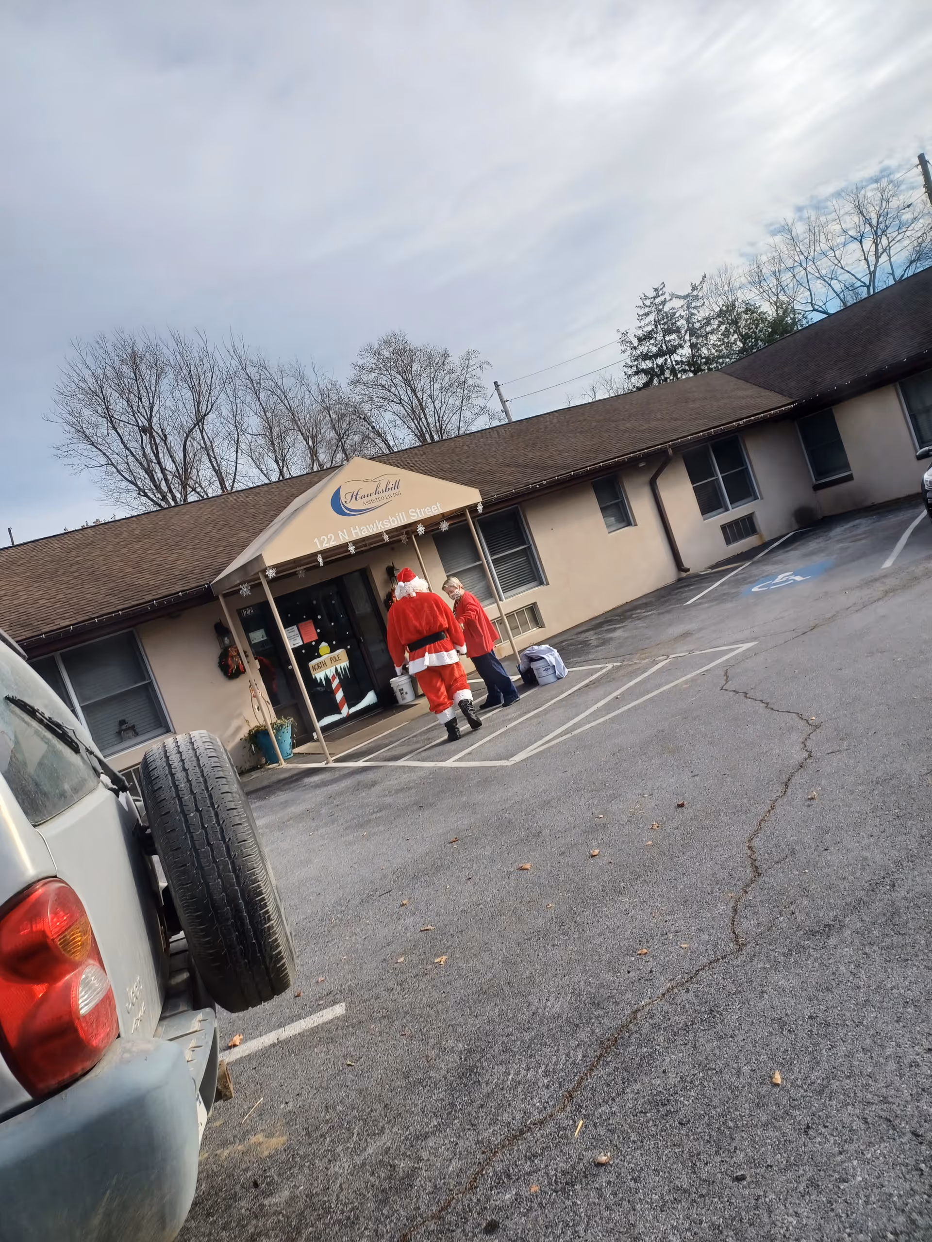 Exterior view of Hawksbill Assisted Living entrance with two people in Santa costumes.