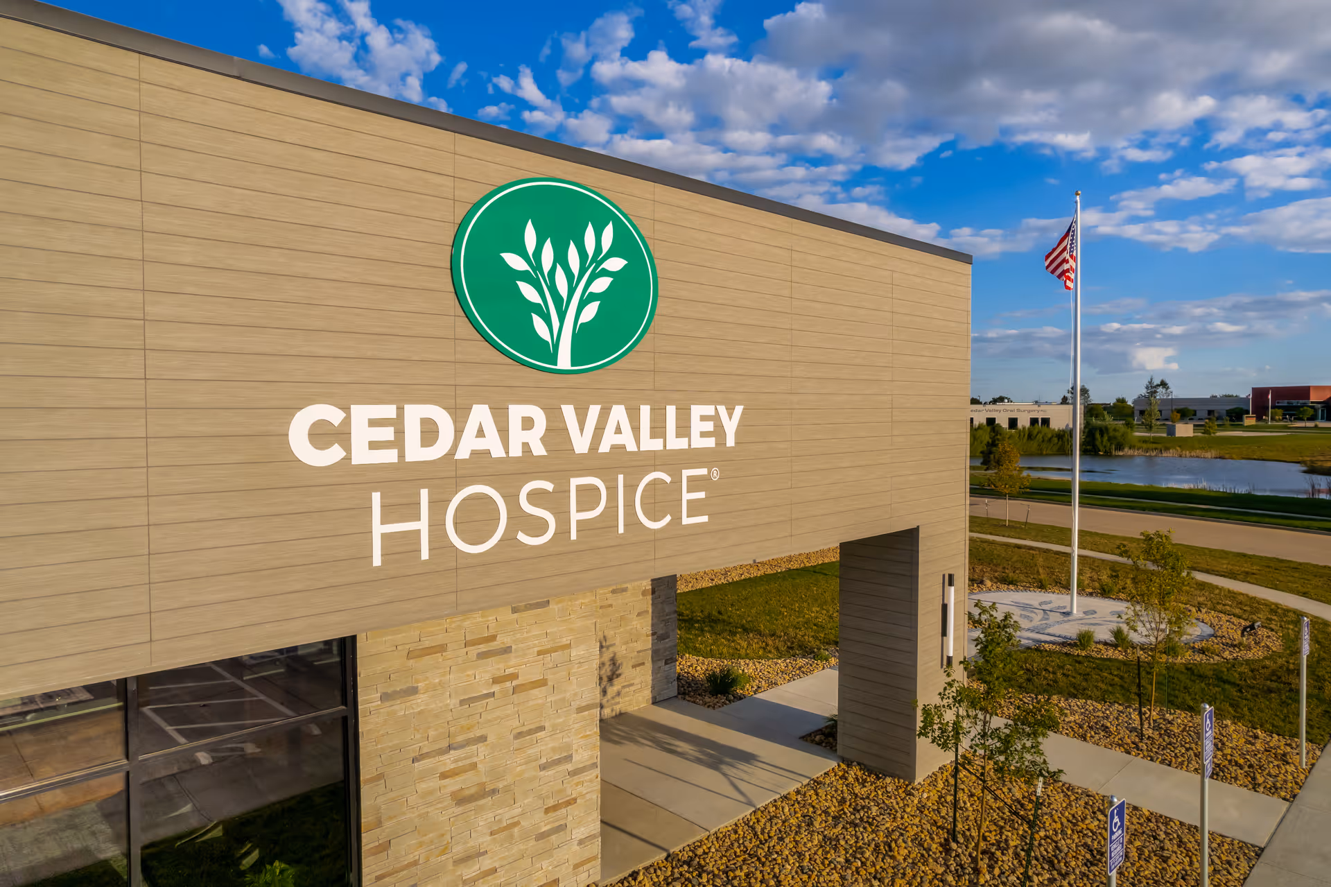Exterior view of Cedar Valley Hospice building with a green circular logo sign.