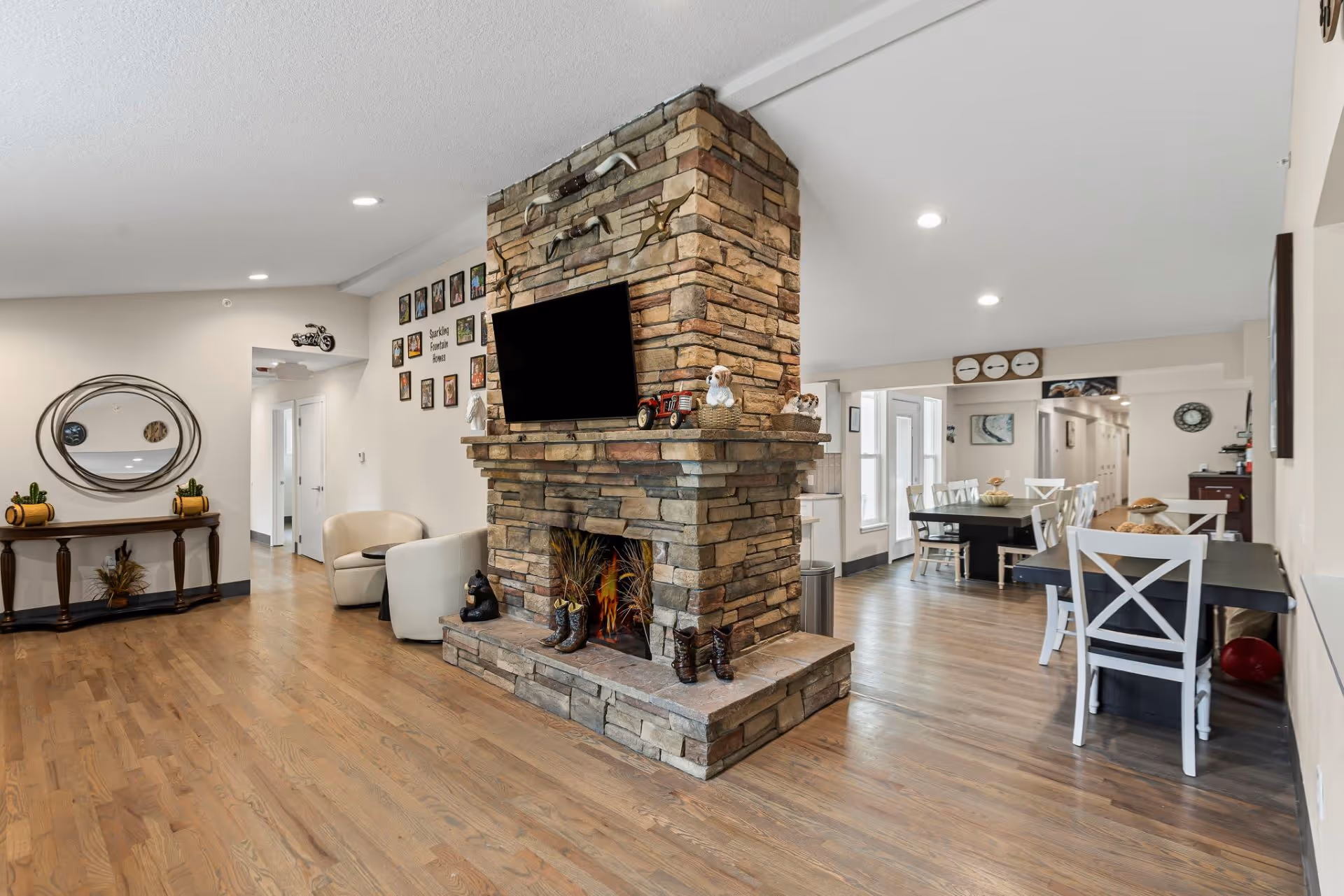 Spacious common living area with a stone fireplace, TV, seating, and dining tables.
