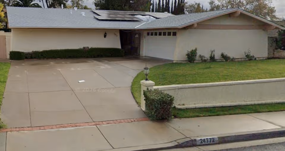 A single-story residential-style building with curved driveway, front lawn, and attached garage.