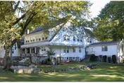 Front exterior of Greenwood Nursing & Rehabilitation Center, a white multi-story building with trees.