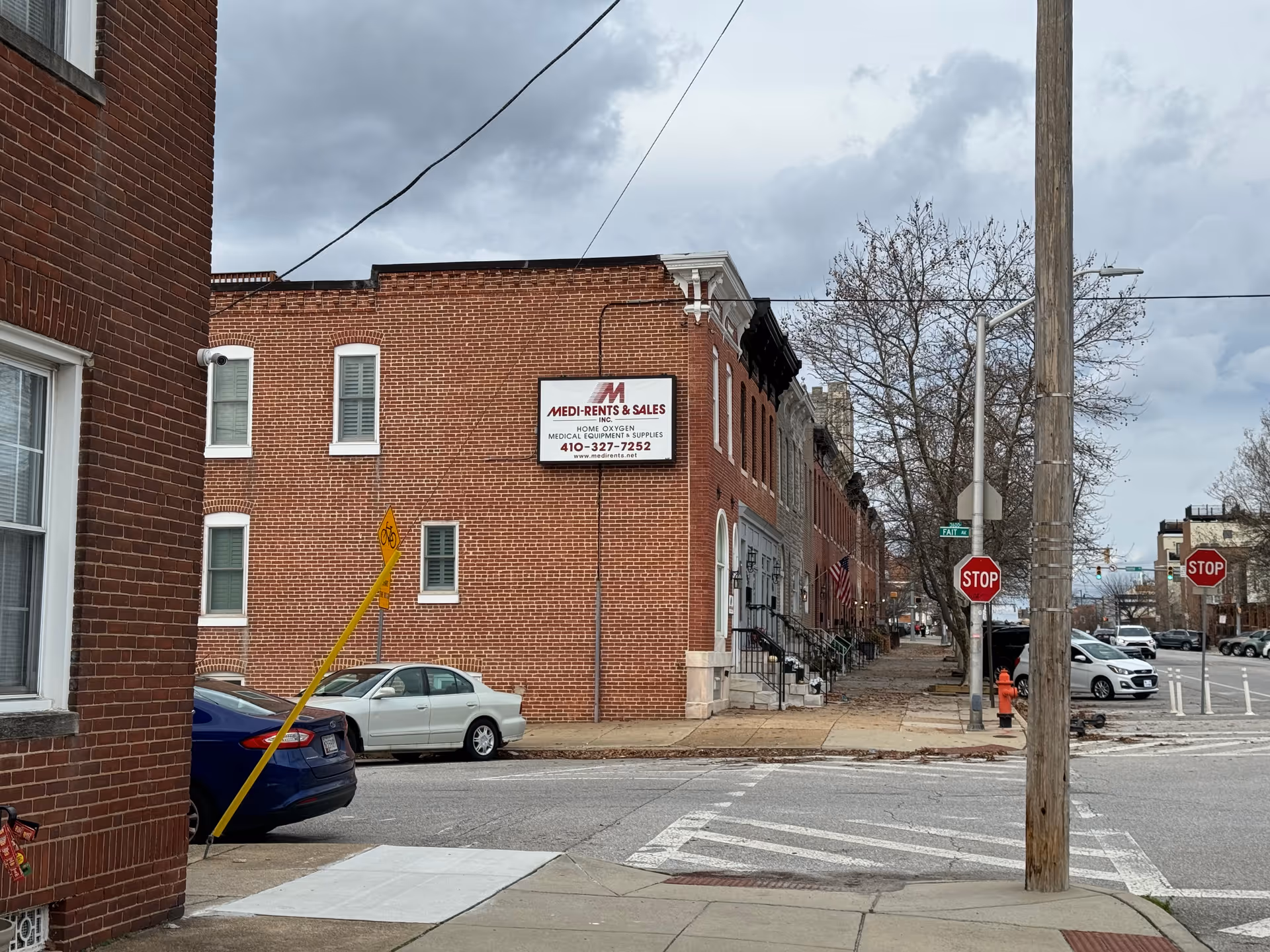 Brick building along a city street with a Medi-Rents sign and parked cars.