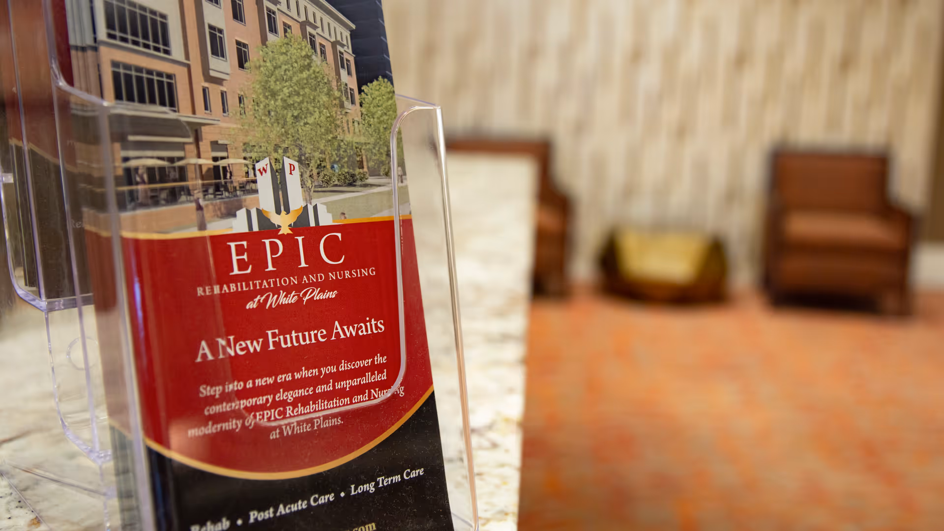 Promotional brochure for Epic Rehabilitation and Nursing at White Plains in a blurred indoor lobby.
