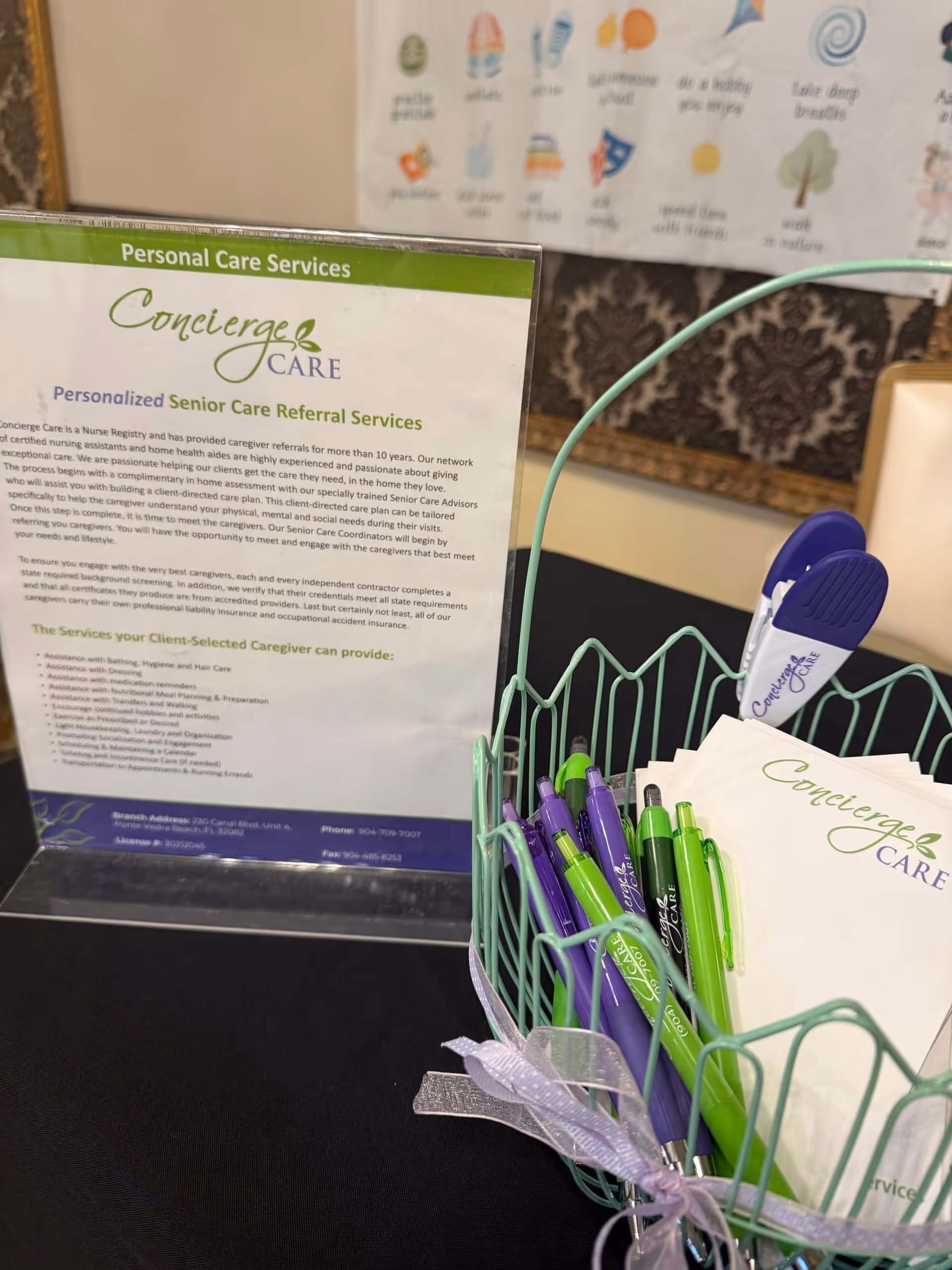 Indoor reception area with Concierge Care sign, brochure stand, and pen basket on a table.