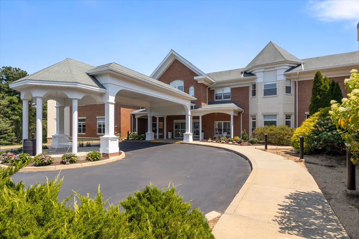 Brick senior living building with curved driveway and covered entrance under a porte-cochère