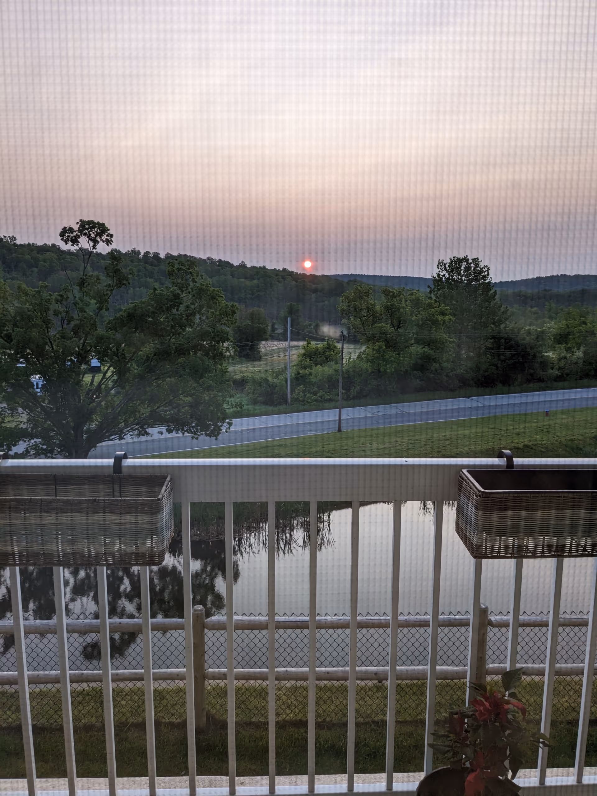 Sunset over Chauncy Lake seen from a balcony with wicker planters.