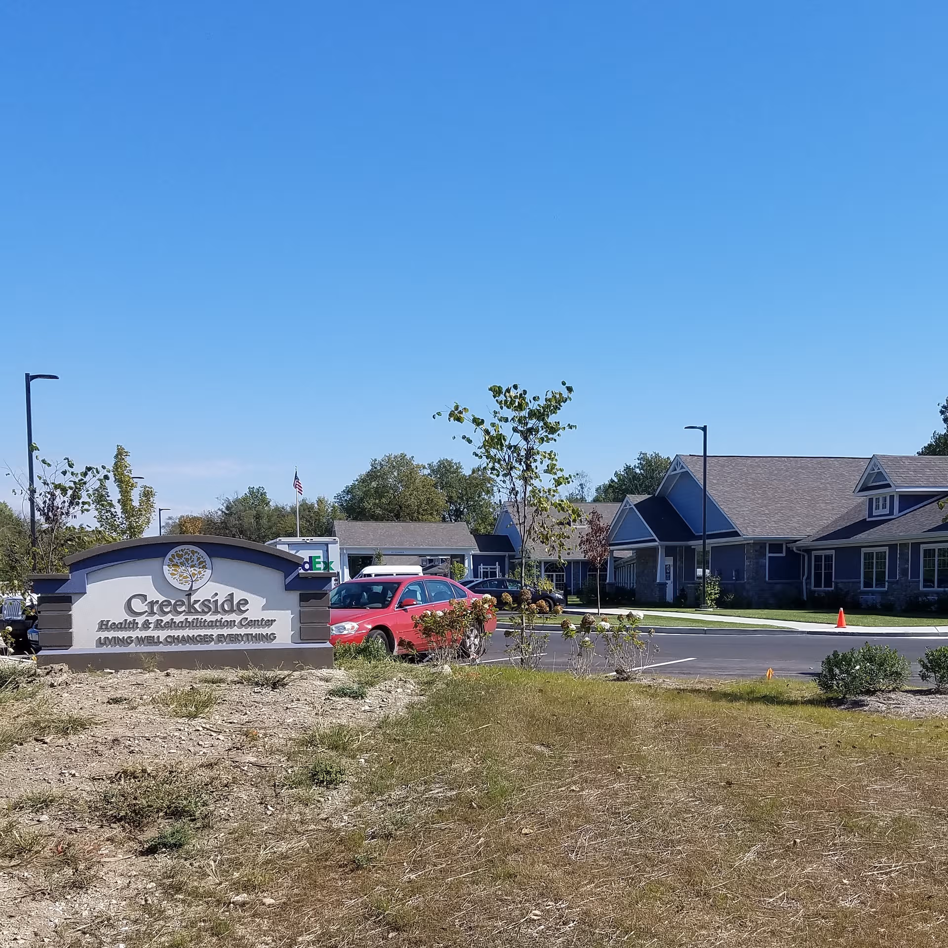 Exterior view of Creekside Health and Rehabilitation Center with sign and parked cars.