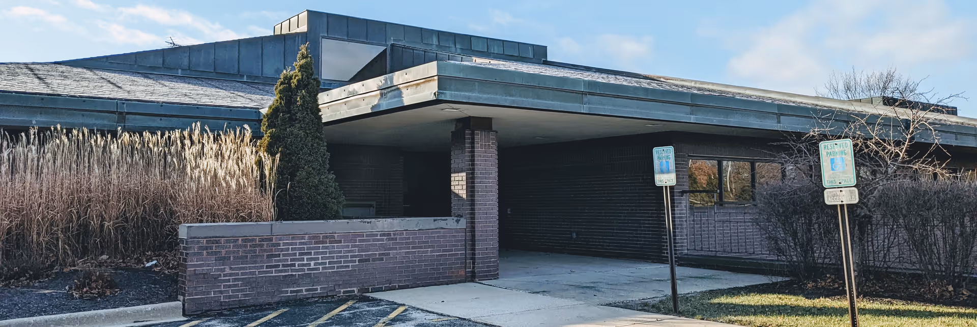 Castle Hospice building exterior with brick walls, covered entrance, and parking area.