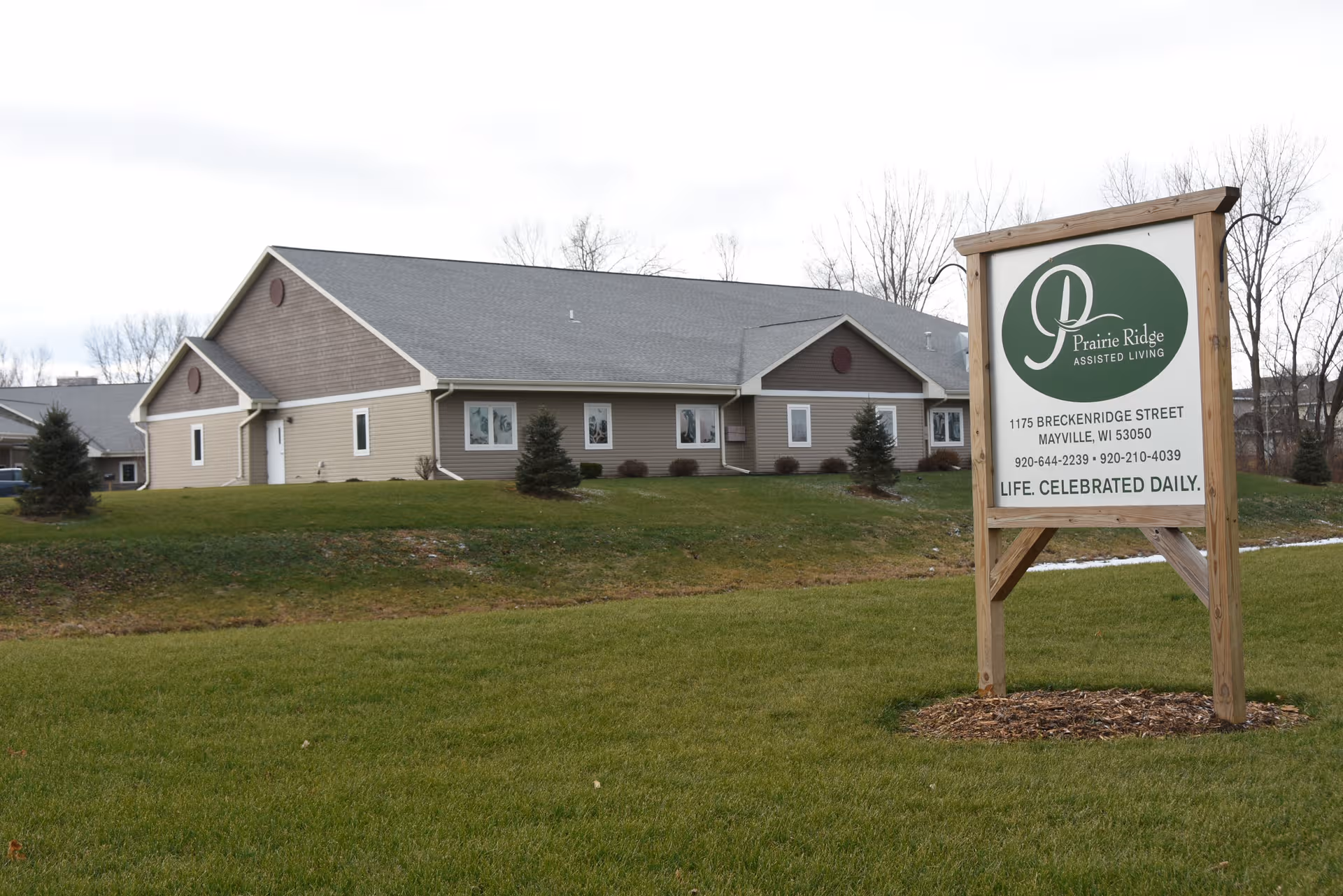 Front view of Prairie Ridge Assisted Living building with sign on a grassy lawn.