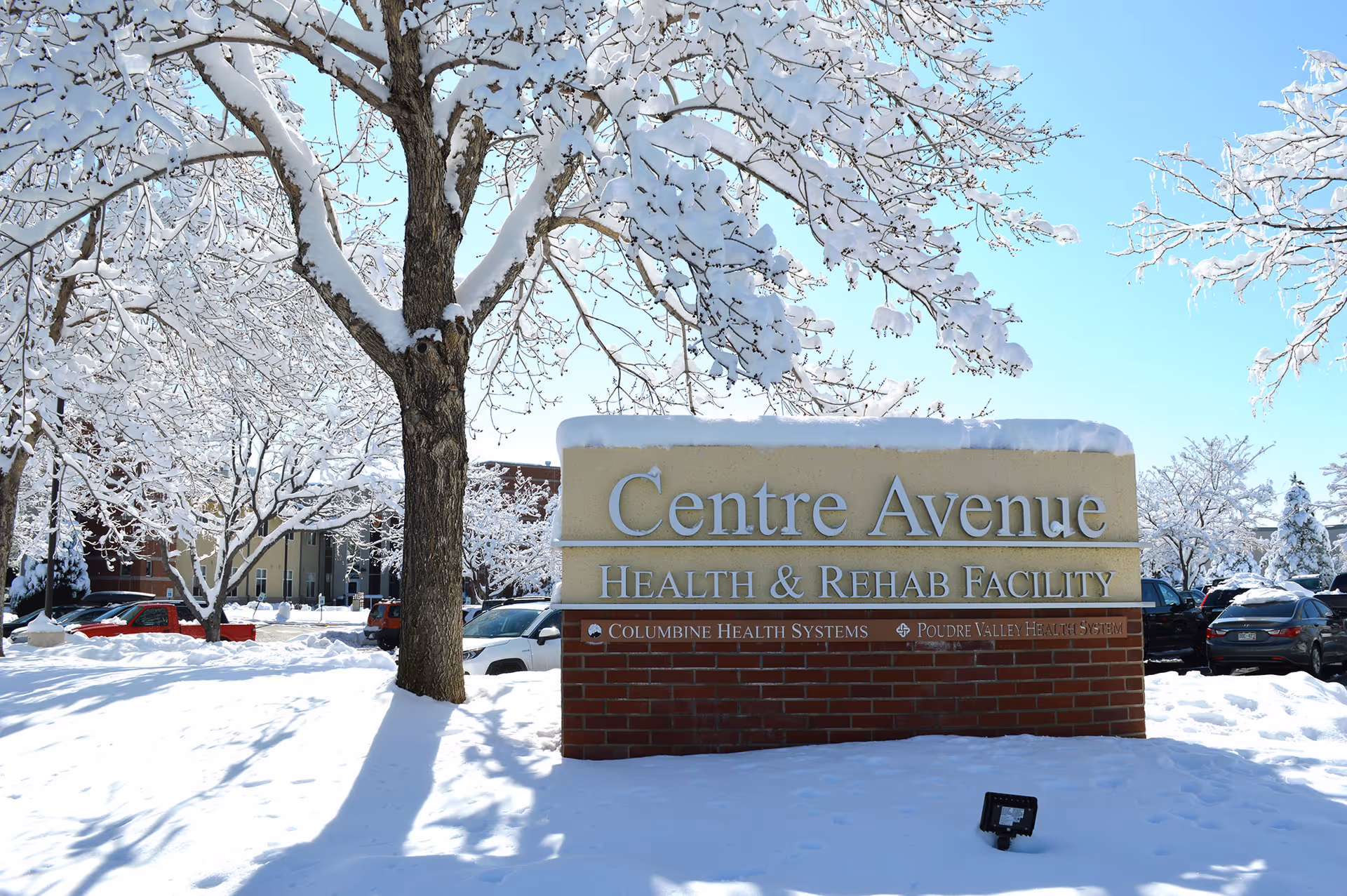 Snow-covered entrance sign for Centre Avenue Health & Rehab Facility in winter