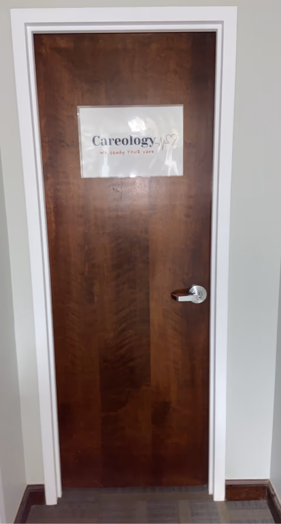 Wooden interior door with a Careology sign mounted on it.