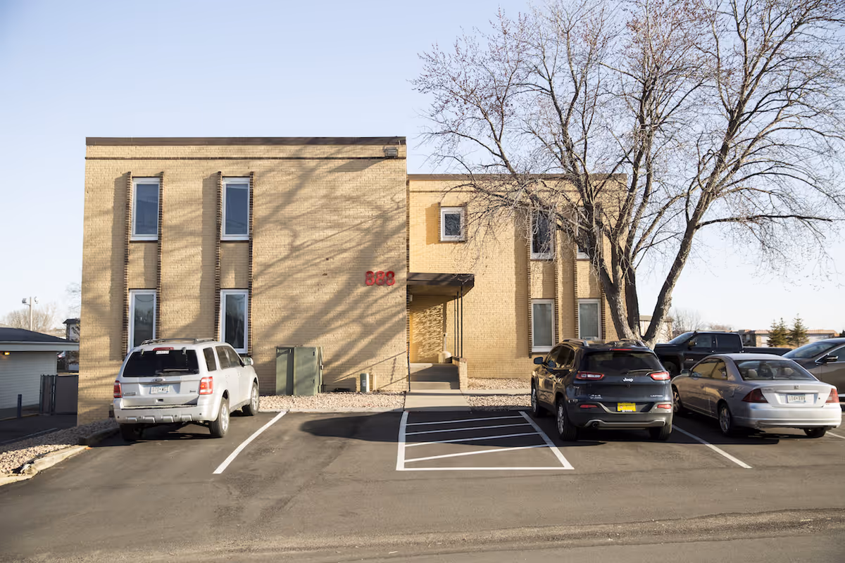 Exterior view of a brick senior facility with a parking lot and entrance.