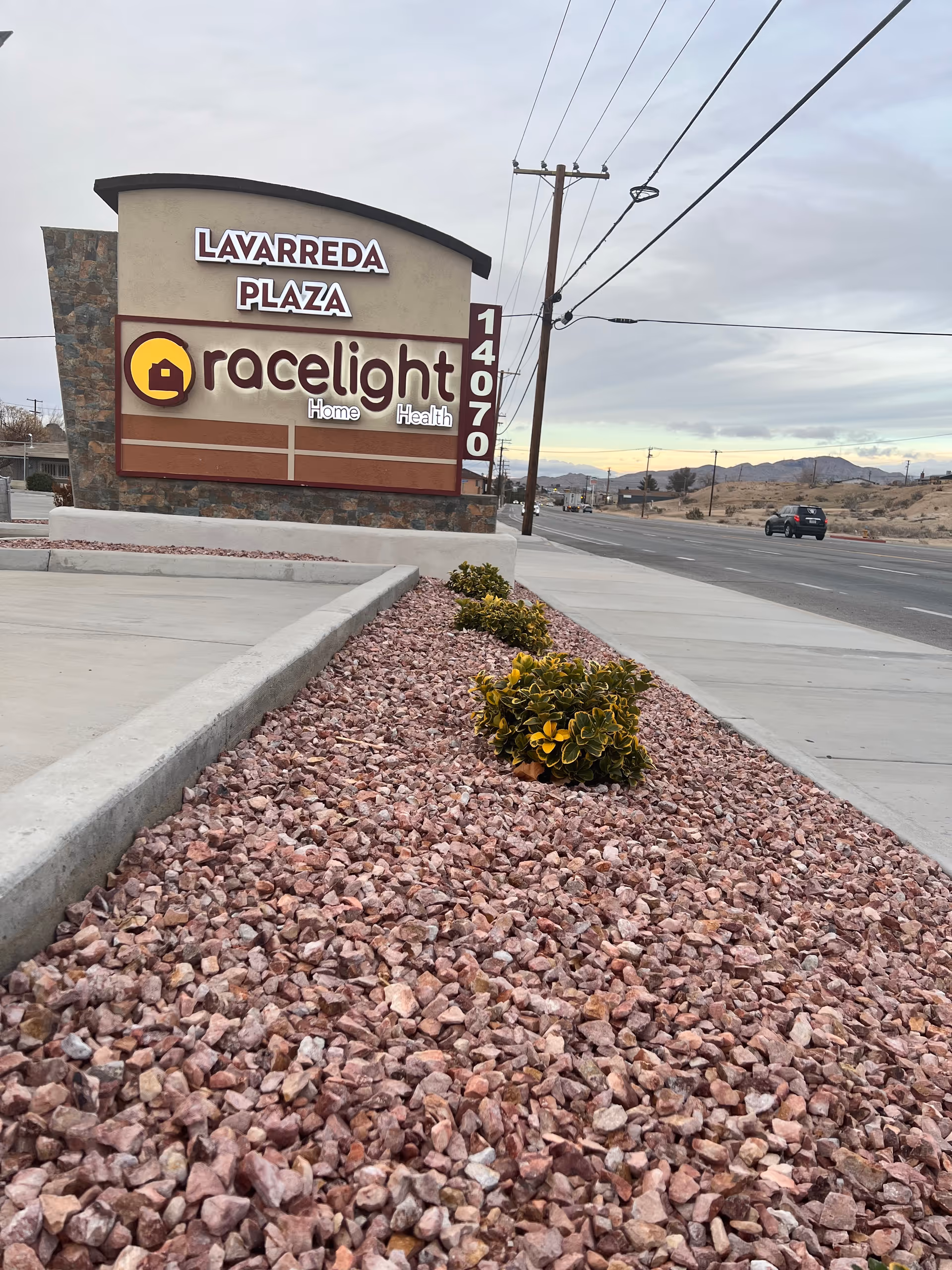 Exterior sign for Lavarreda Plaza and Gracelight Home Health along a desert road.