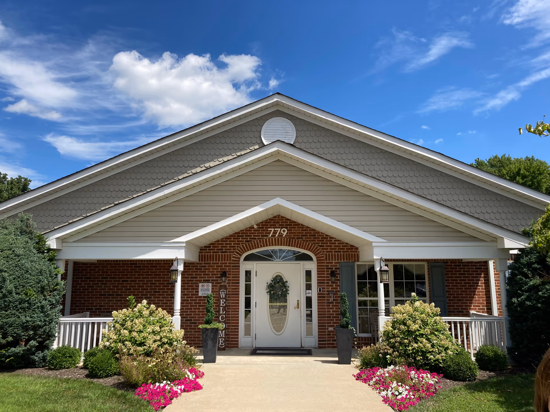 Front exterior of Arden Courts Warminster facility with brick entrance, plants, and flowers.