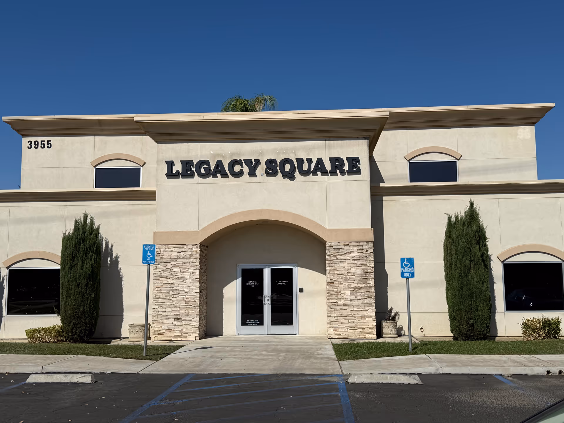 Front view of a beige building labeled Legacy Square with an arched entrance.