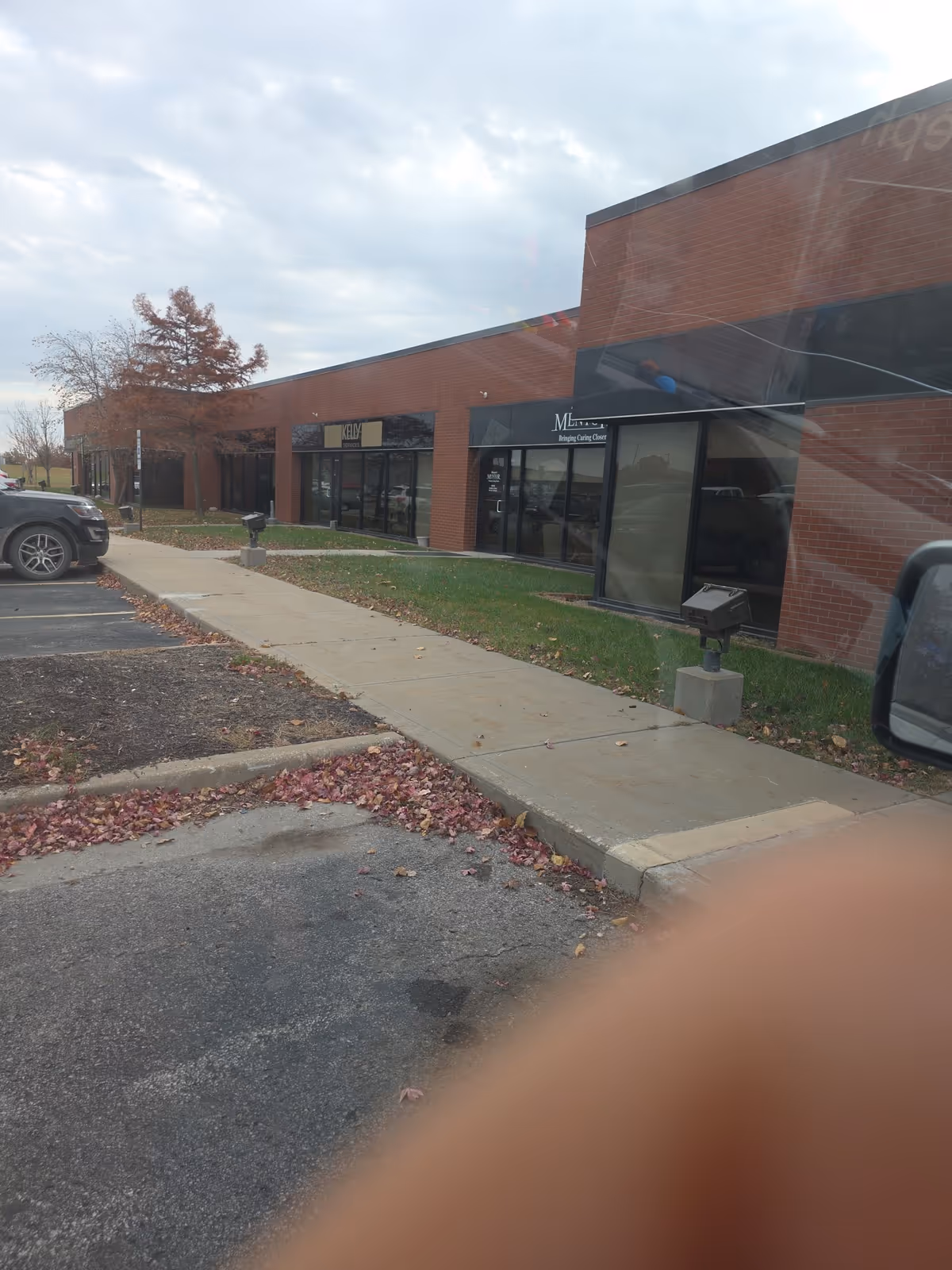 Brick Mosaic Life Care Home Health exterior with sidewalk, parking, and large storefront windows.