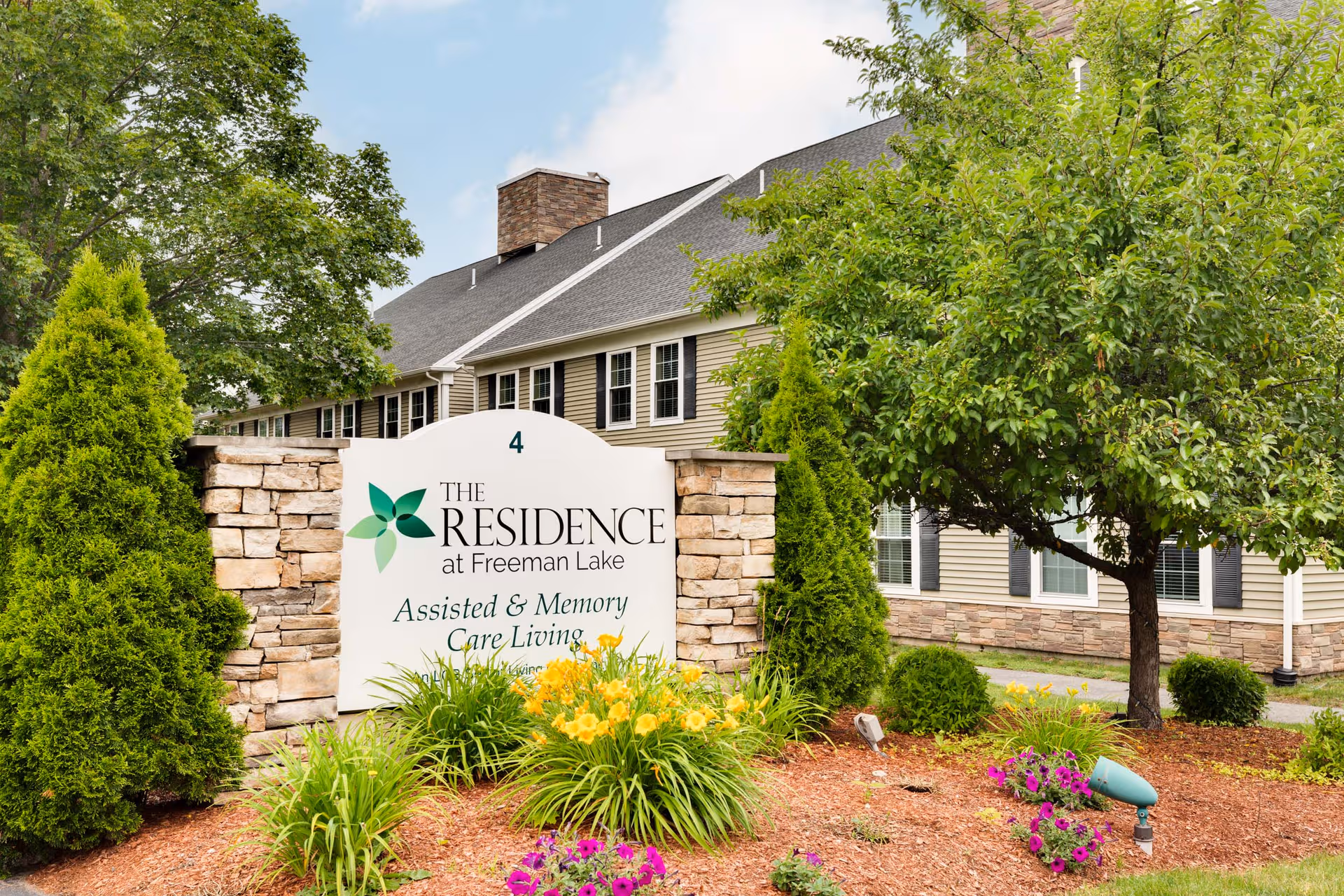 Exterior view of The Residence at Freeman Lake with a landscaped entrance sign.