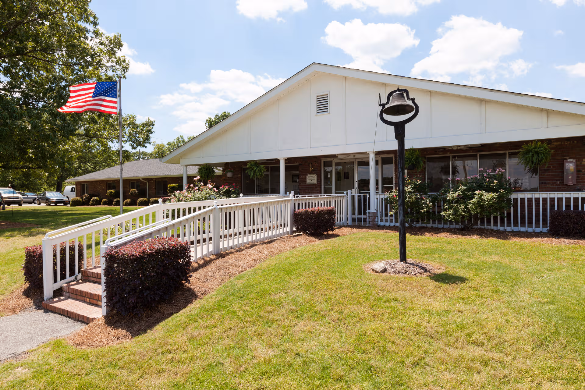 Front exterior of PruittHealth Monroe with ramp, flag, and porch.
