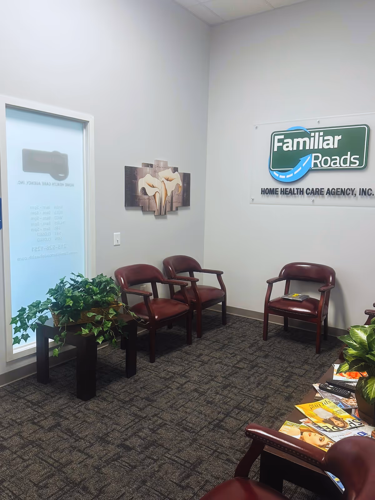 Interior waiting area with burgundy chairs, plants, and a Familiar Roads sign.