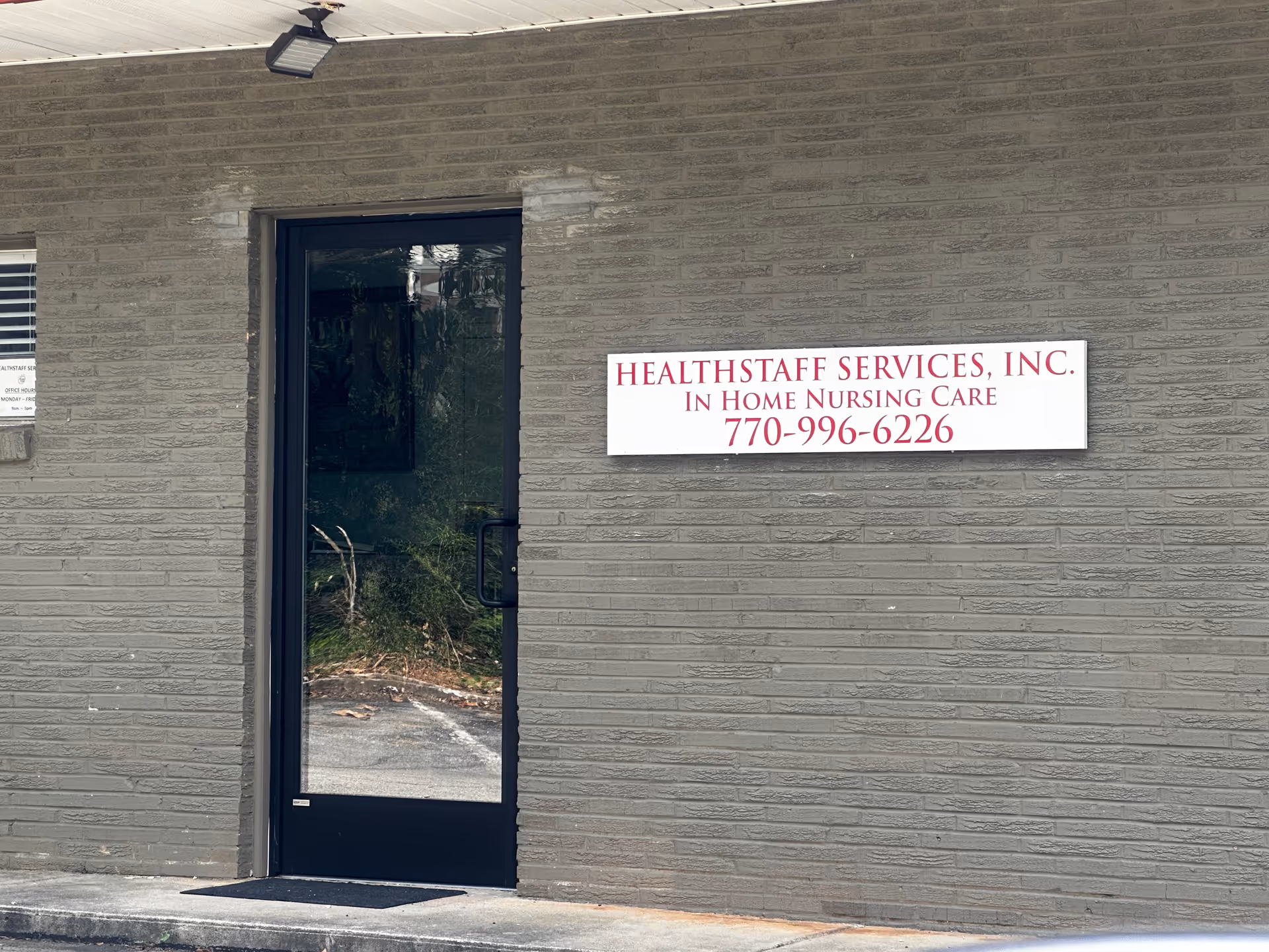 Grey brick building exterior with a glass door and Healthstaff Services sign.