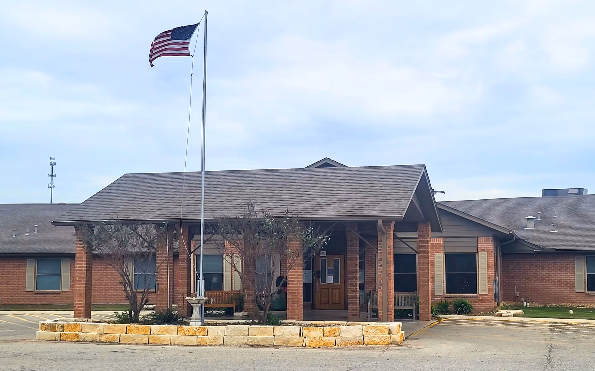 Single-story brick senior care facility with flagpole and covered entrance.