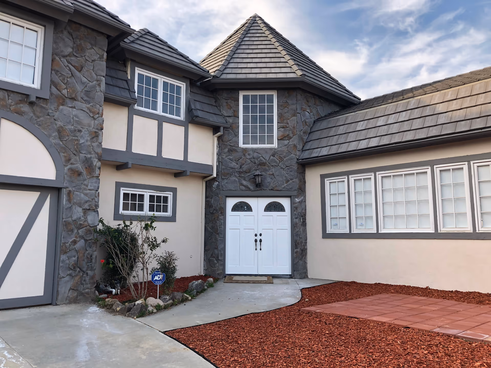 Facade of Ohana Senior Assisted Living with stone walls, windows, double doors, and red mulch walkway.