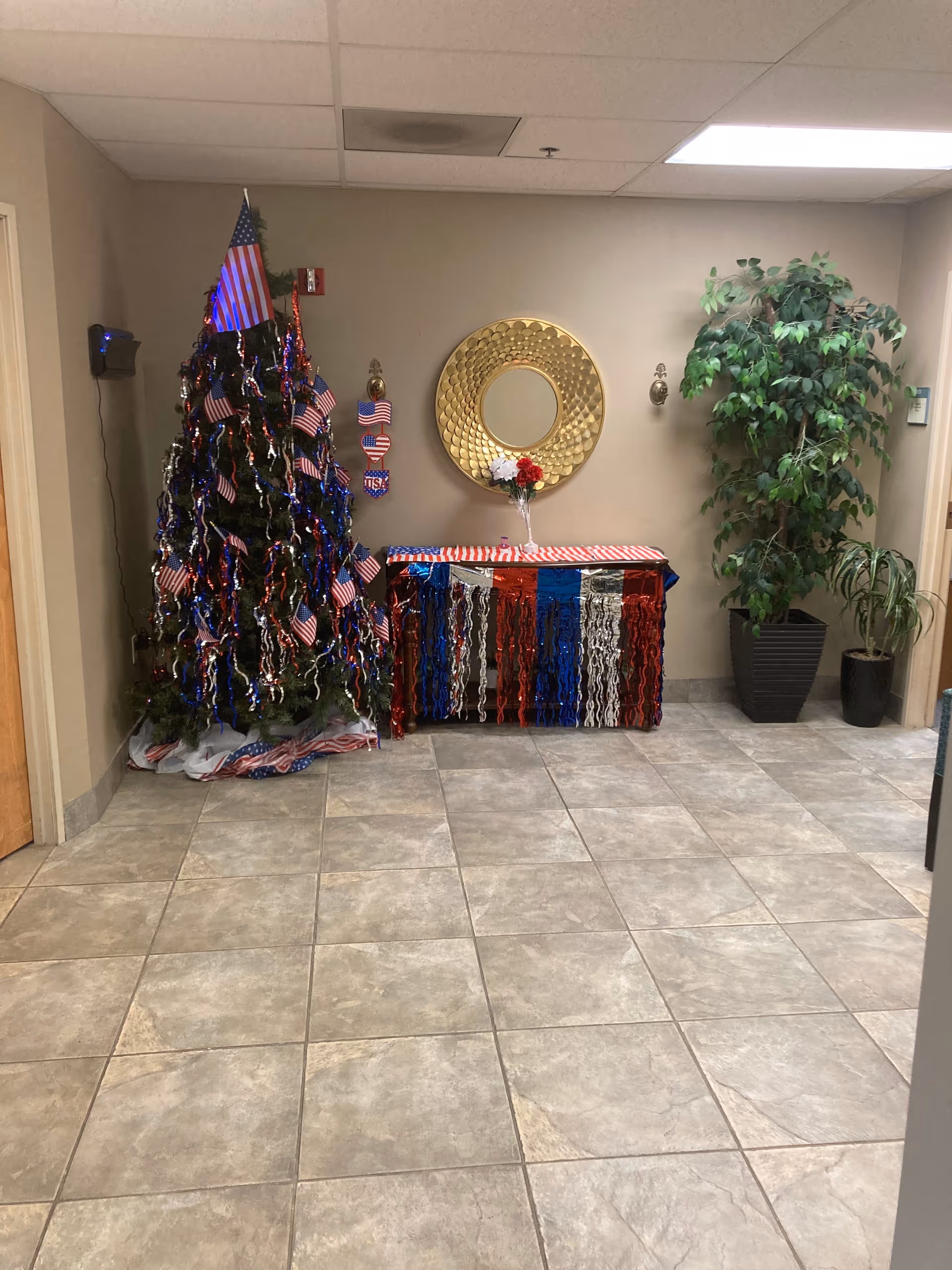 Patriotic holiday display with an American flag-decorated Christmas tree, and a gold circular mirror.