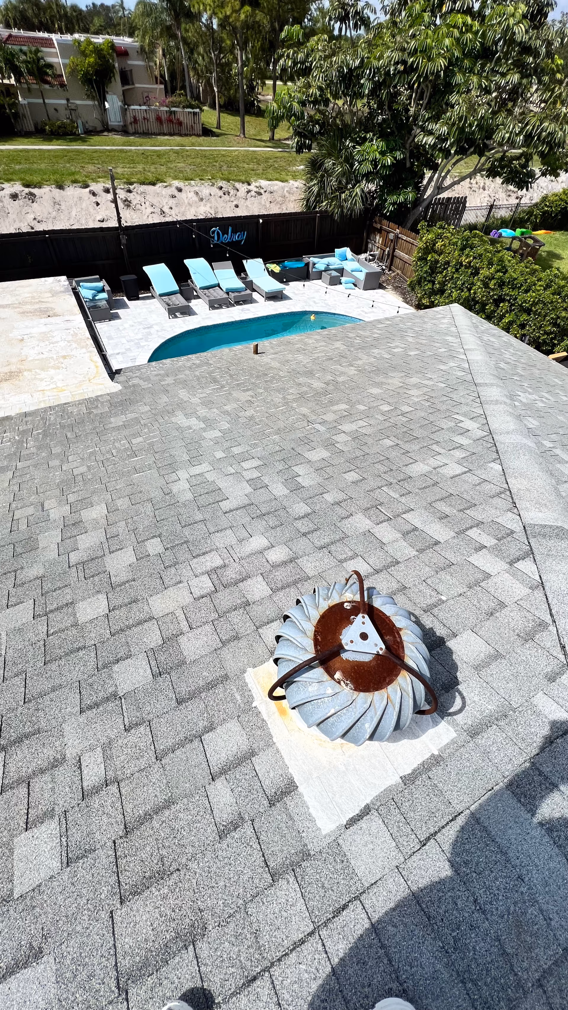 Overhead view of a rooftop pool area with lounge chairs and a vent.
