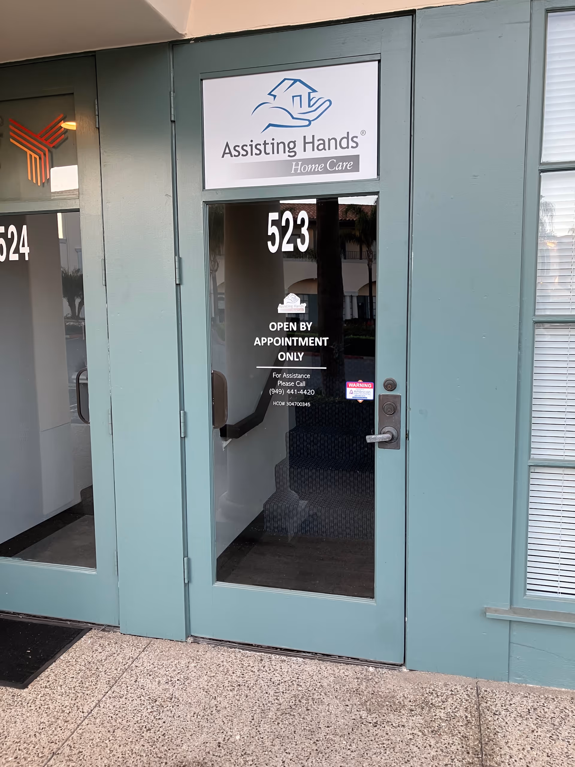 Glass door with Assisting Hands Home Care sign and building number 523 at the entrance.