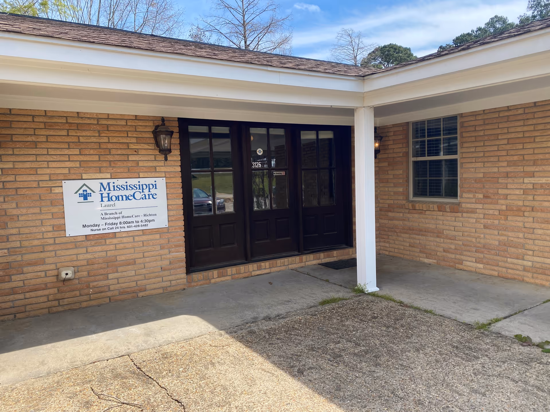 Brick exterior of Mississippi HomeCare Laurel entrance with double black doors and sign.