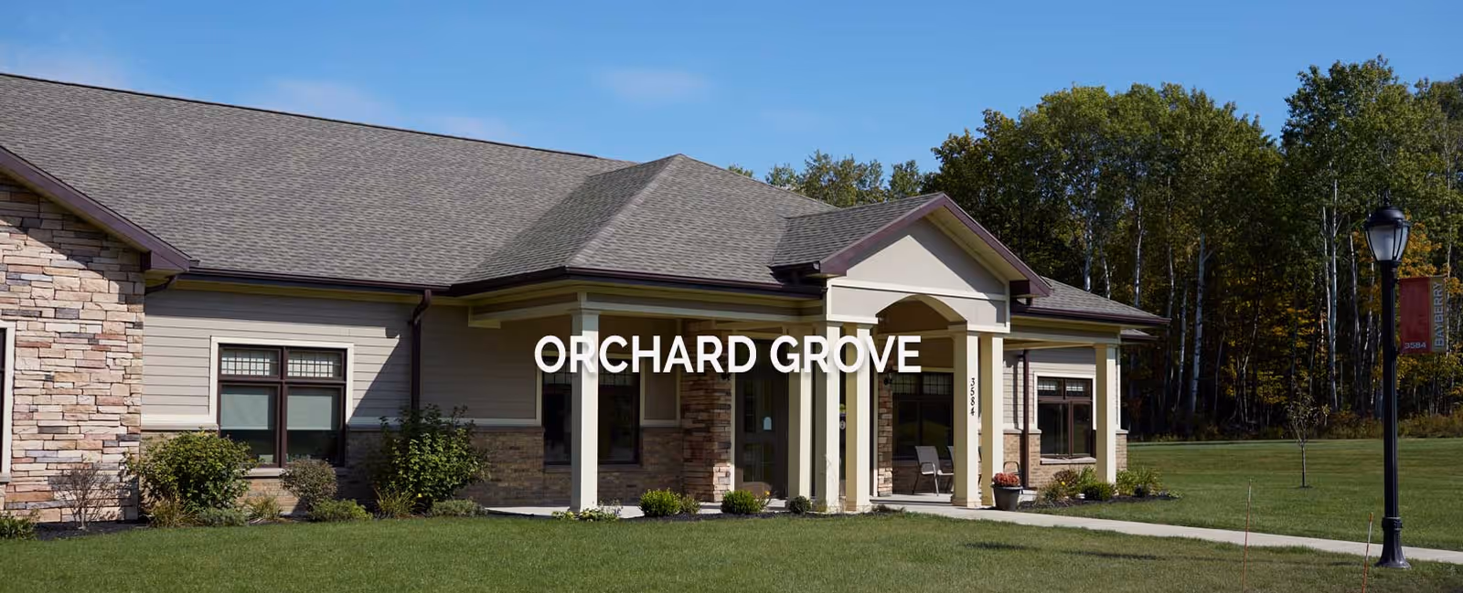 Single-story senior living facility exterior with a front entrance and manicured lawn.