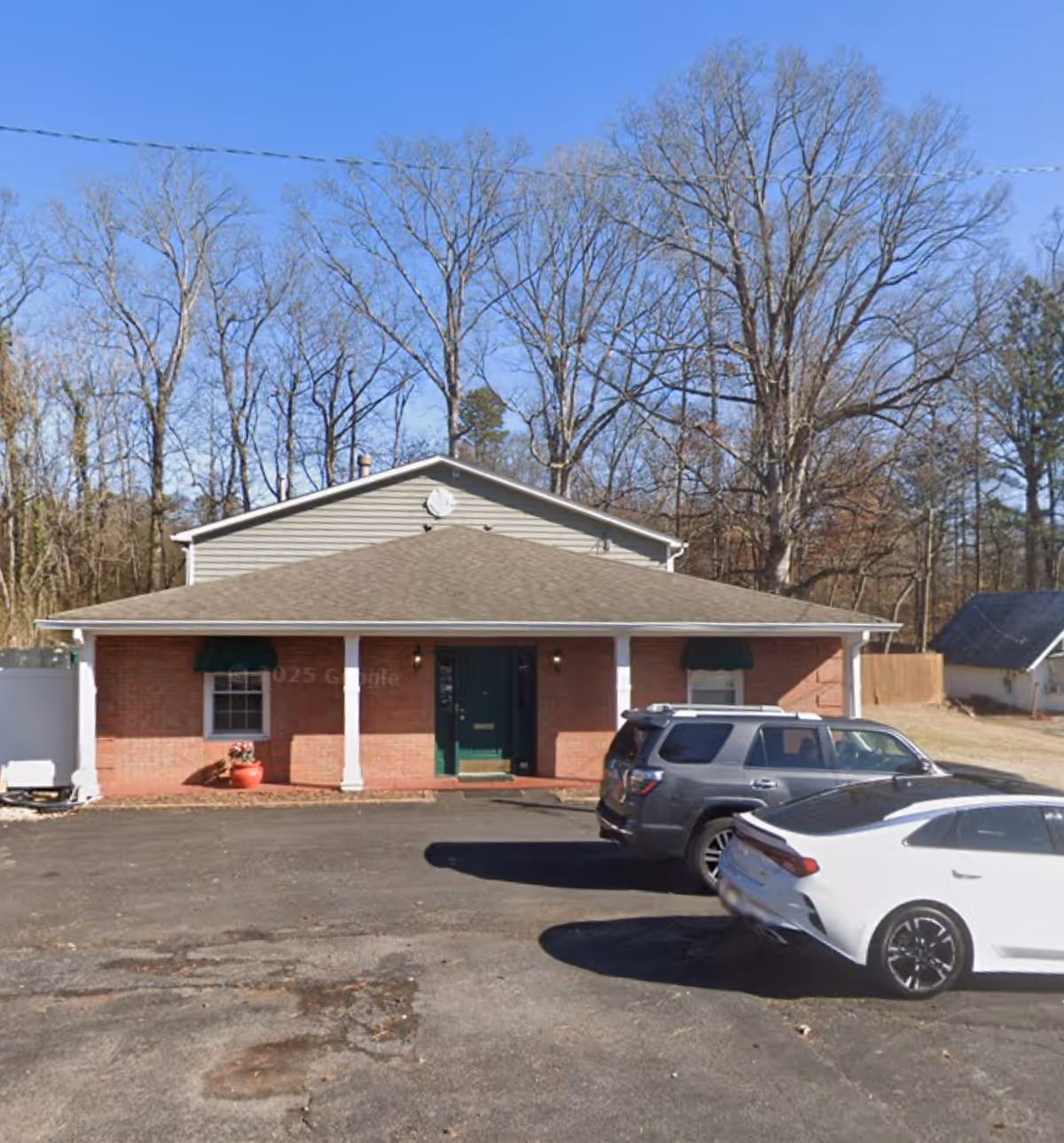 Brick, single-story facility with green awning and cars parked in front lot.