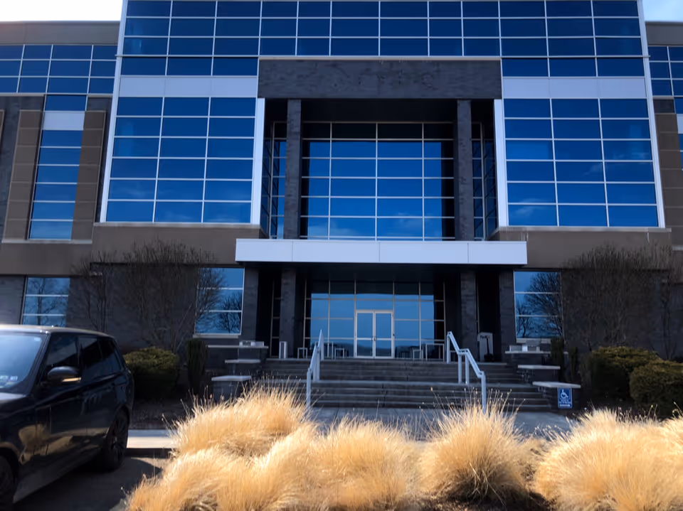 Front view of a modern glass-front building with steps and a wide entrance.
