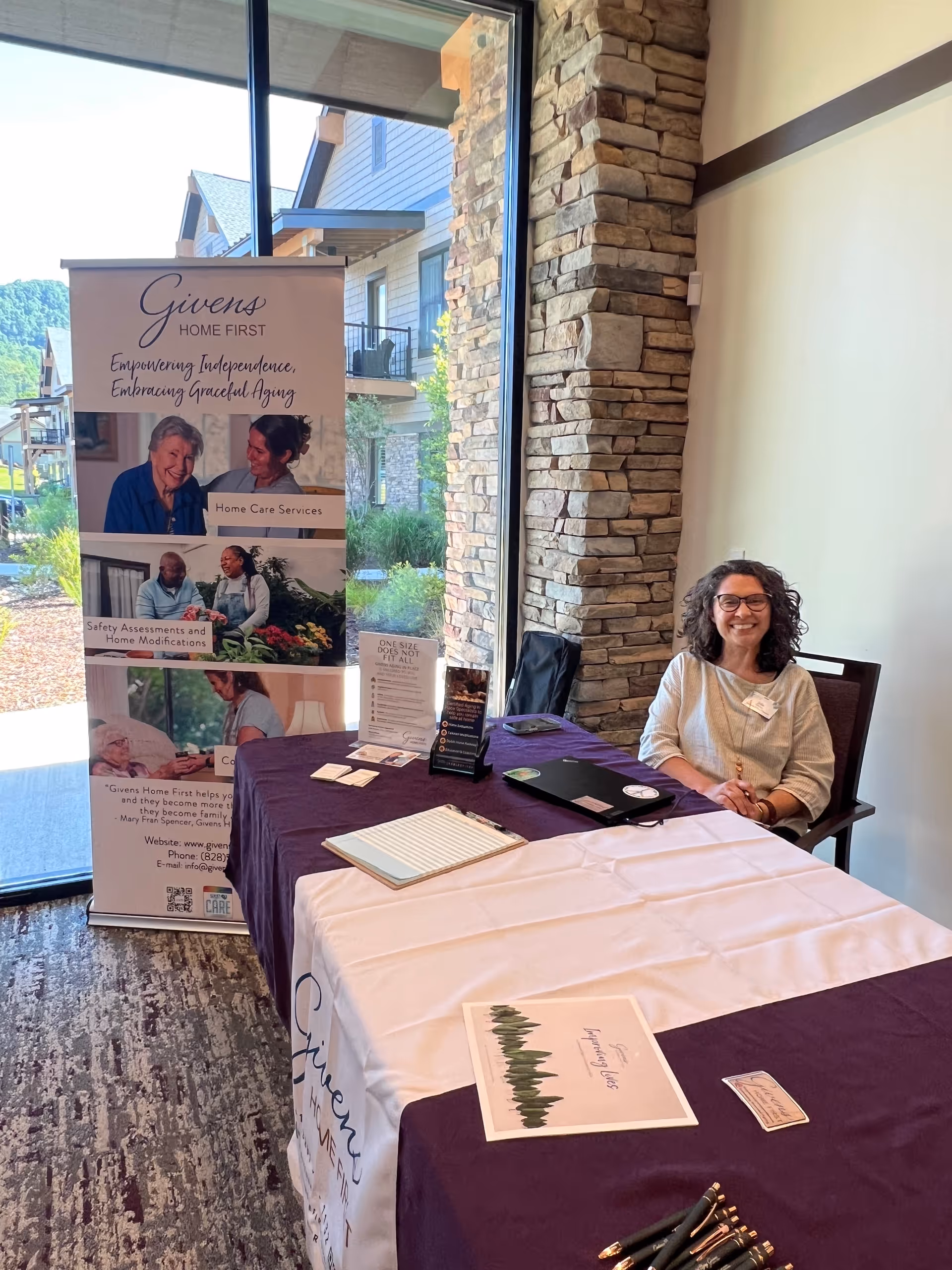 Indoor booth for Givens Home First featuring banner, table setup, and smiling staff.