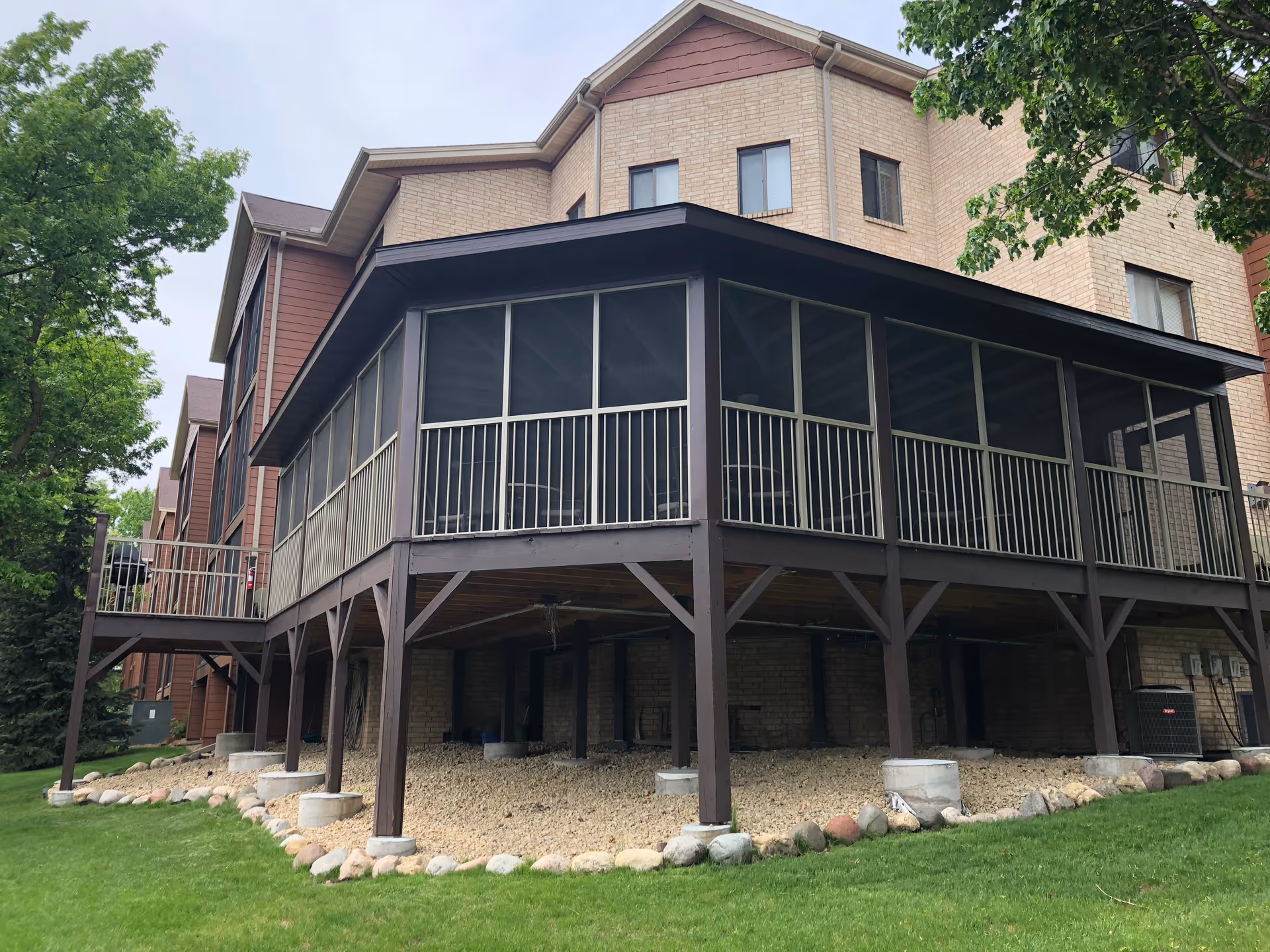 Two-story brick senior living building with a large screened porch on raised posts.