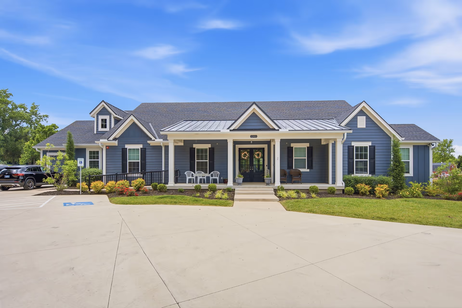 Blue single-story senior living facility with a front porch and parking