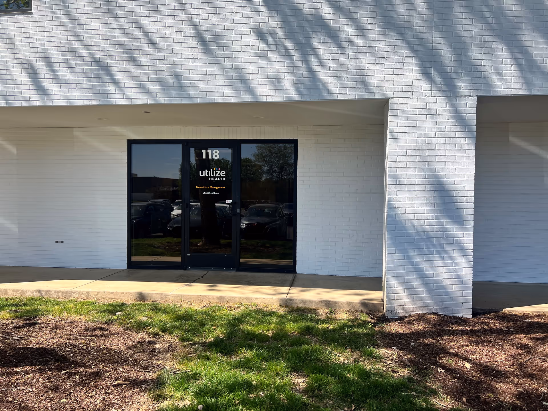 White brick building exterior with glass doors and Utilize Health sign.