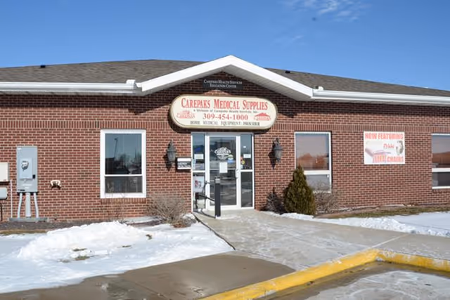 Brick storefront with Carepaks Medical Supplies sign above glass entrance, snow-covered sidewalk.