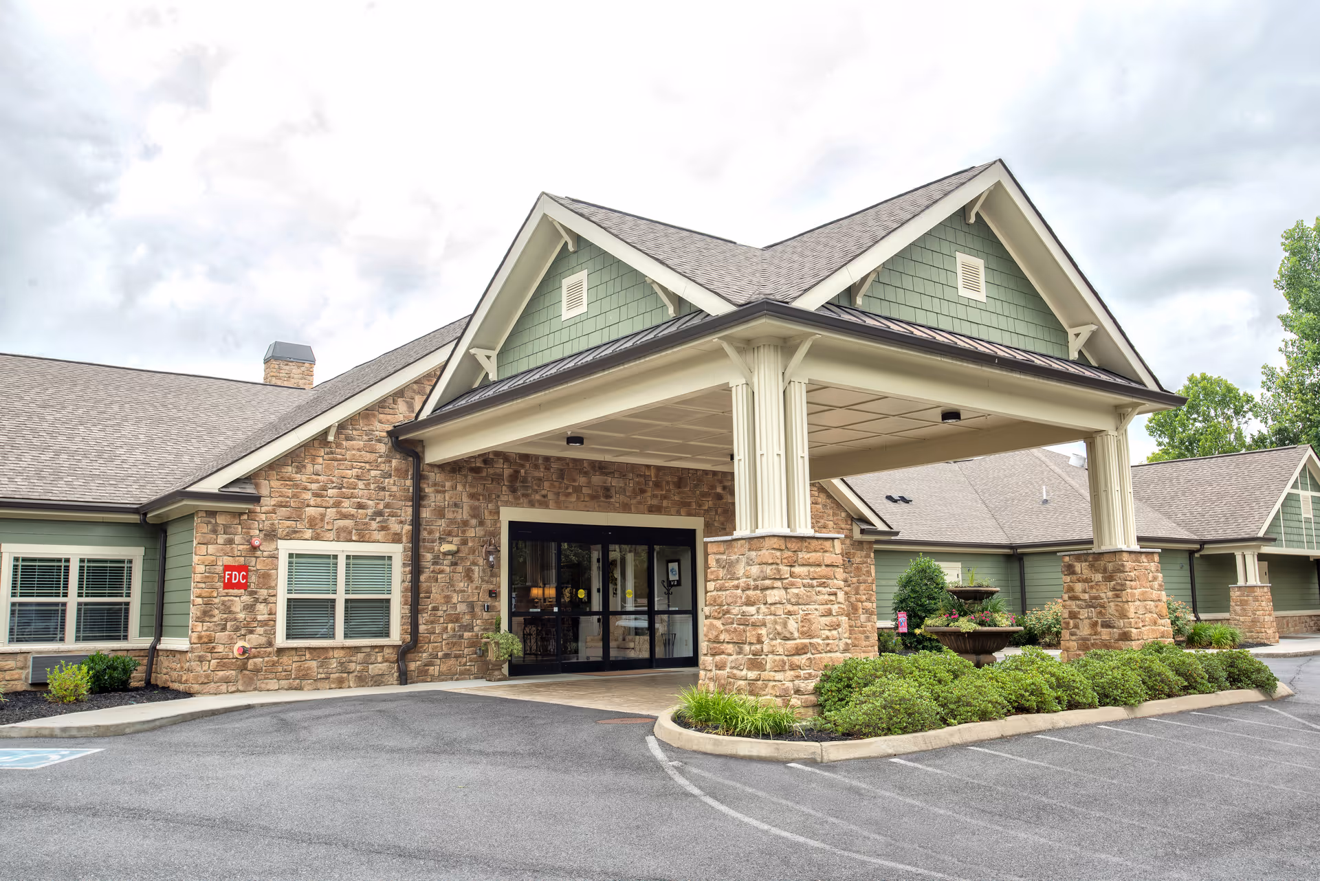 Exterior view of Dominion Senior Living entrance with stone columns and landscaping.